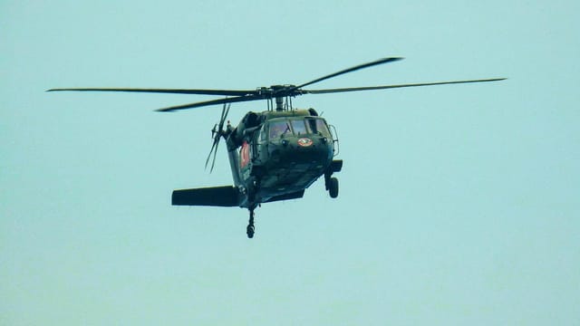 A military helicopter flying through a clear sky, showcasing aviation technology.