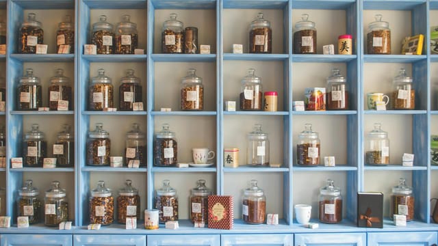 Organized display of herbal tea jars on vibrant blue shelves in a shop.