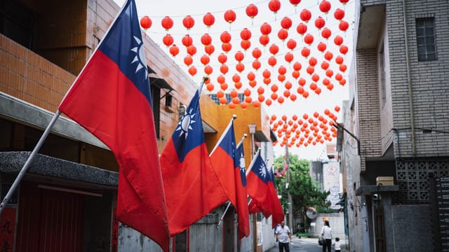 Colorful Taiwanese flags and red lanterns adorn an alley in New Taipei City, Taiwan, creating a festive atmosphere.