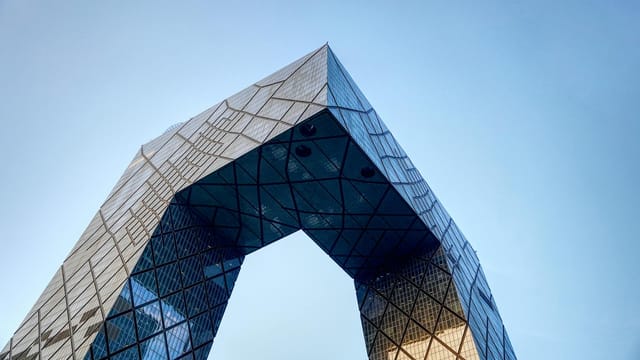 Low-angle view of the iconic CCTV Headquarters against a clear blue sky in Beijing.