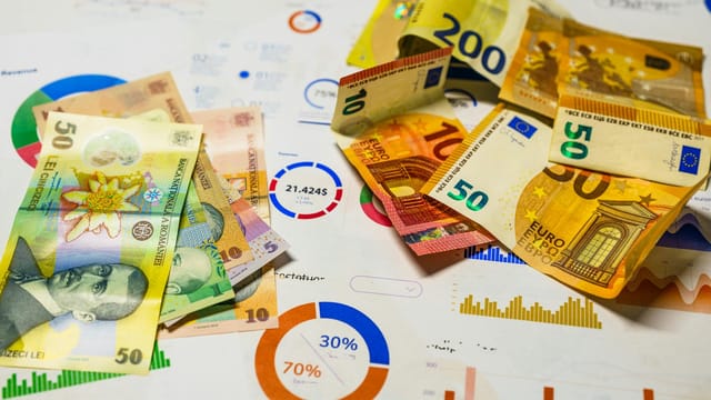 Colorful Euro and Romanian Lei banknotes on top of financial charts, symbolizing currency exchange and economic analysis.