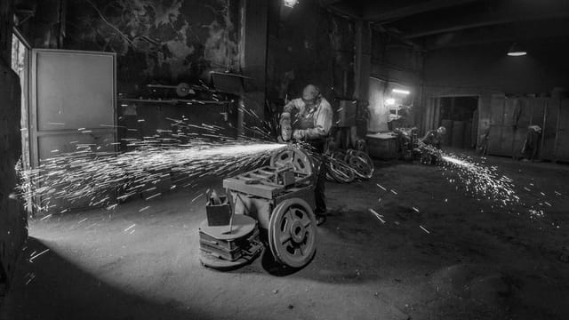 A worker using a grinder in a gritty industrial setting, sparks flying.