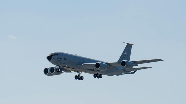 A US Air Force aircraft flies against a clear blue sky, showcasing air superiority and aviation technology.