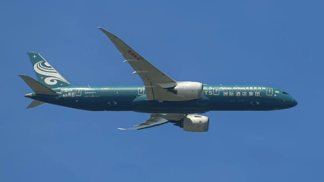A sleek passenger airplane in flight against a clear blue sky.