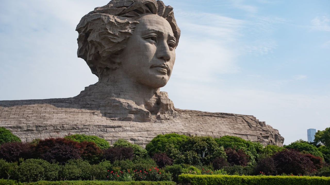 Large stone statue of a prominent figure set amidst a lush park landscape.