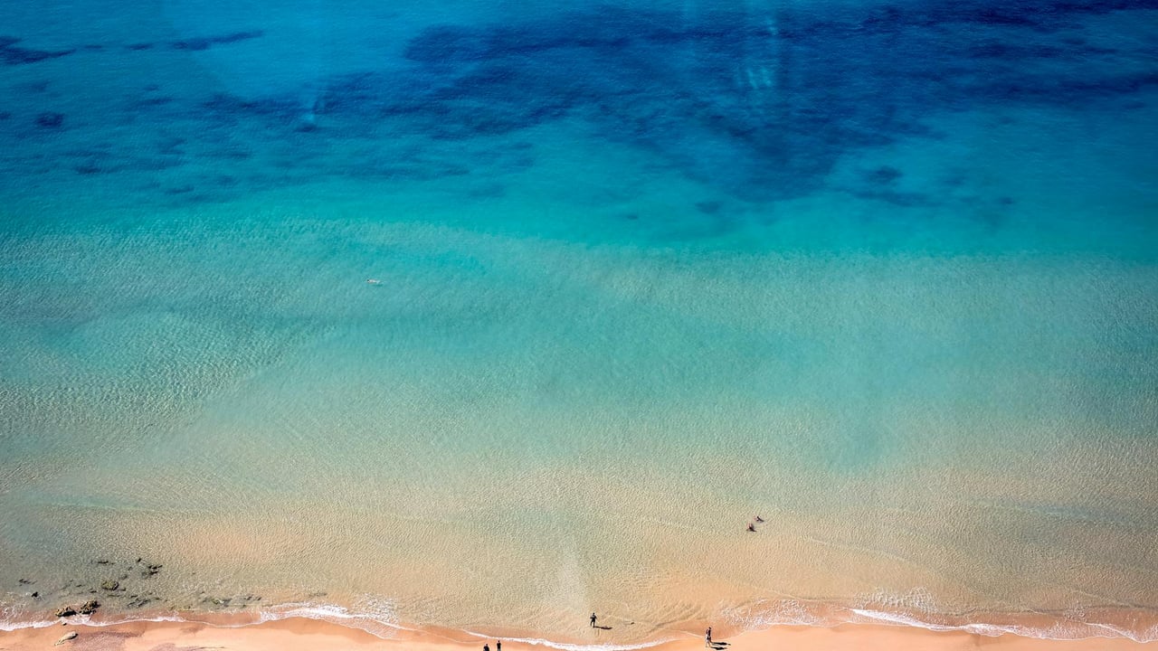 A stunning aerial shot of a turquoise beach in Israel, showcasing golden sands and clear waters.