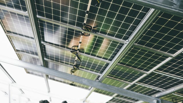 Close-up of solar panels being installed outdoors with technicians visible.