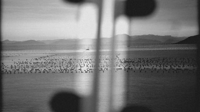 Moody black and white seascape with distant mountains in Fujian, China.