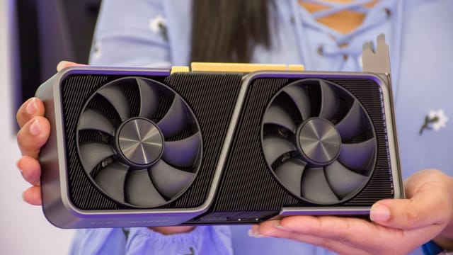 Detailed shot of hands holding a modern graphics card indoors.