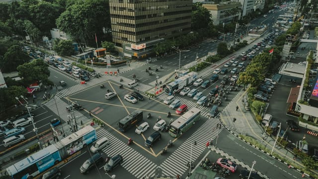 A bustling aerial view of a busy traffic intersection in Jakarta, Indonesia filled with vehicles and pedestrians.