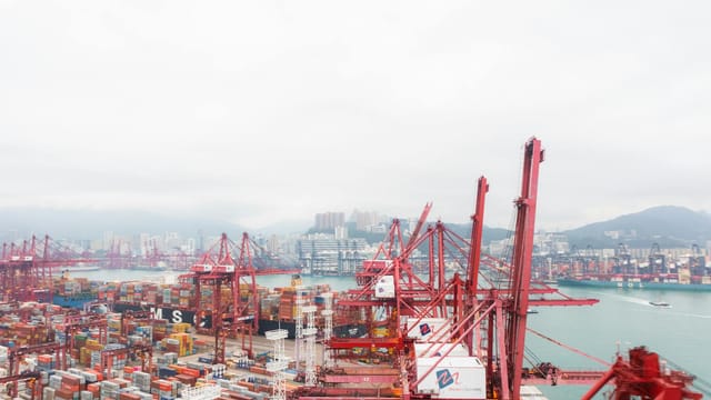 A vibrant harbor view showcasing cranes and shipping containers at a busy port.