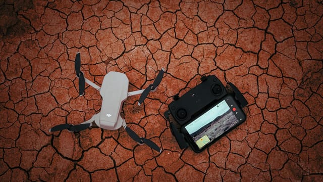Drone with controller on a dry, cracked ground illustrating modern technology usage in harsh environments.