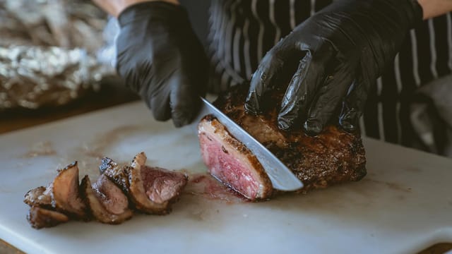 Chef slicing a perfectly cooked steak on a chopping board, showcasing juicy and delicious meat.