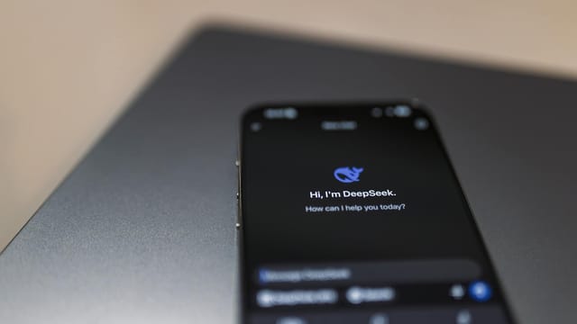 Close-up of a smartphone with AI assistant interface on screen over a laptop.