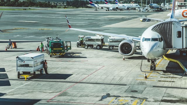 Ground crew preparing a commercial airplane for departure at an airport tarmac.