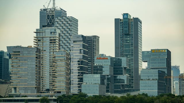 Skyline featuring modern skyscrapers with prominent logos of major companies.