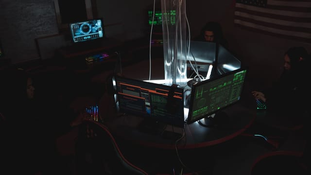 Team of cybersecurity experts collaboratively working on data protection in a dimly lit room filled with computers.