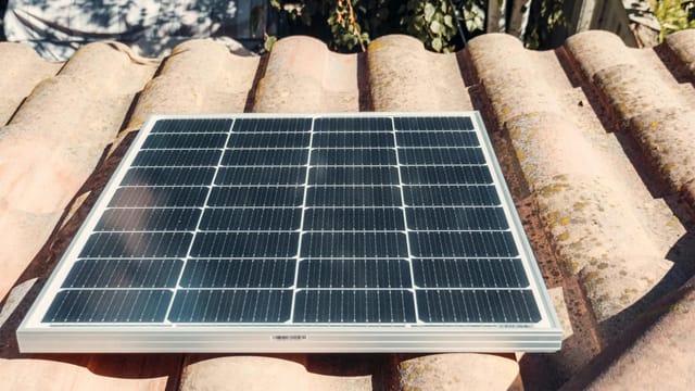 A single solar panel on a rustic tiled roof gleaming in sunlight. Eco-friendly energy.