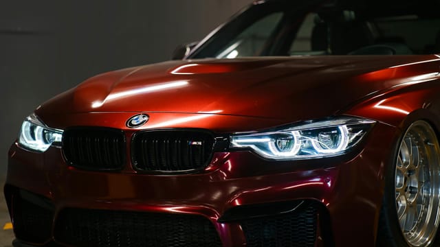 Close-up of a luxury red BMW with a sleek, shiny hood captured indoors.