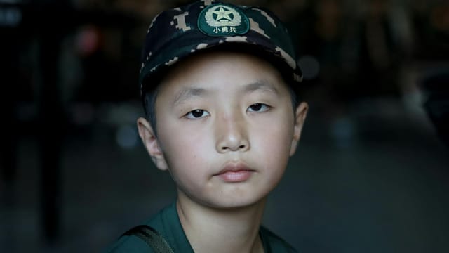 Close-up portrait of an Asian boy wearing a military-inspired cap with copyspace.