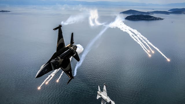Two fighter jets performing an aerial maneuver over the sea in Türkiye.