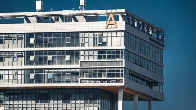 Close-up of a modern office building with glass facade under a clear blue sky.