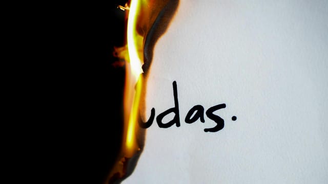 A piece of paper with handwritten text 'udas' partially engulfed in flames.