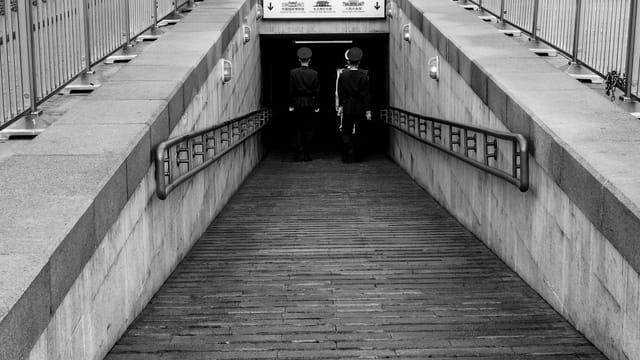 Black and white photo capturing two guards entering a tunnel in Beijing, China.