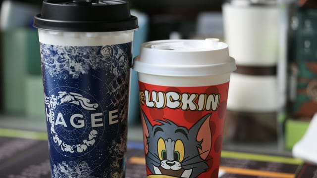 Two colorful branded coffee cups with distinct designs, indoors setting.