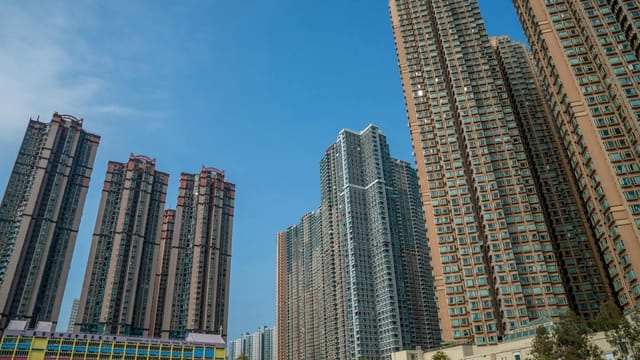 High-rise buildings in Hong Kong under a clear blue sky, showcasing urban density and modern architecture.