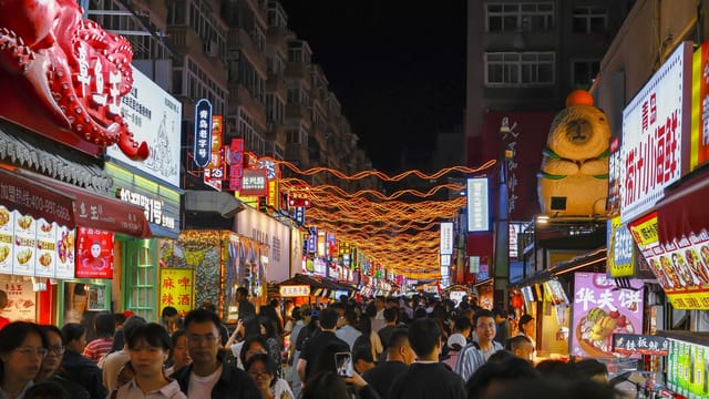 A bustling night market scene filled with people and colorful neon signage, capturing urban nightlife energy.