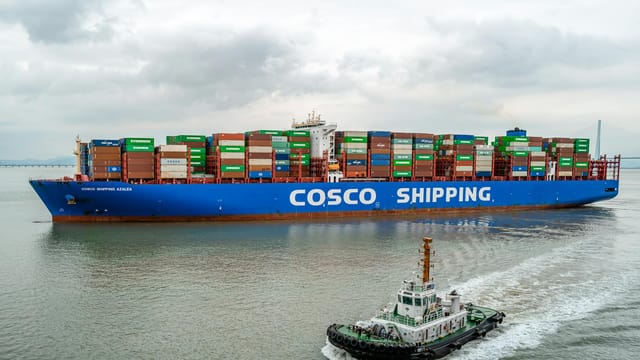 A large COSCO container ship navigates the waters of Ningbo Harbor, China.