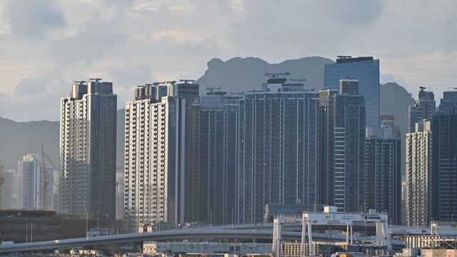 Cityscape featuring towering high-rise buildings against a mountainous backdrop.