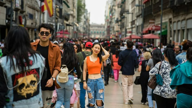 A vibrant street in Mexico City bustling with diverse people enjoying a lively day out.