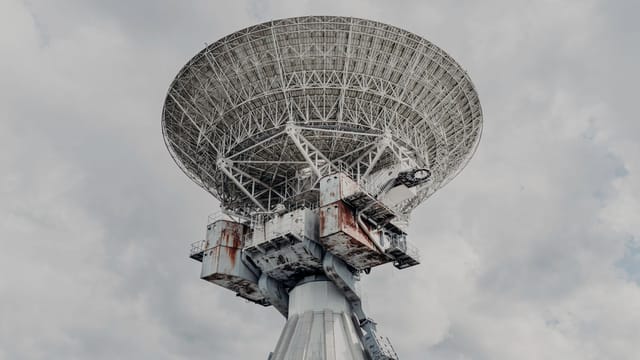 Illustrative image: Close-up of a large radio telescope against a cloudy sky.