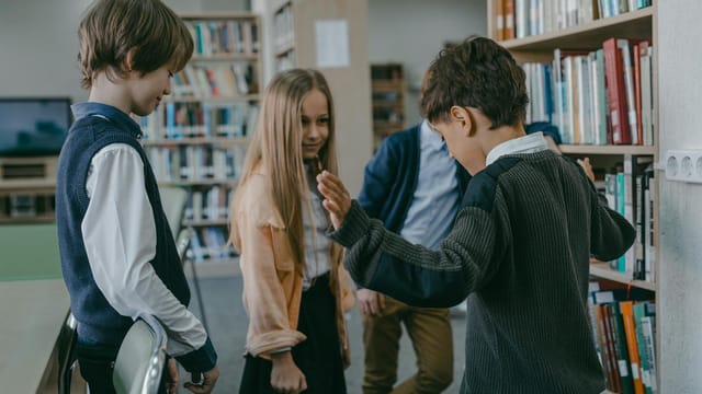 Group of children interacting in a school library, showcasing learning and friendship.