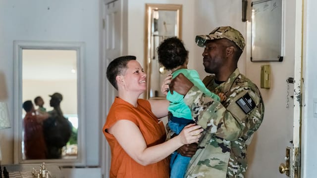 A heartwarming military family reunion with parents and child indoors.