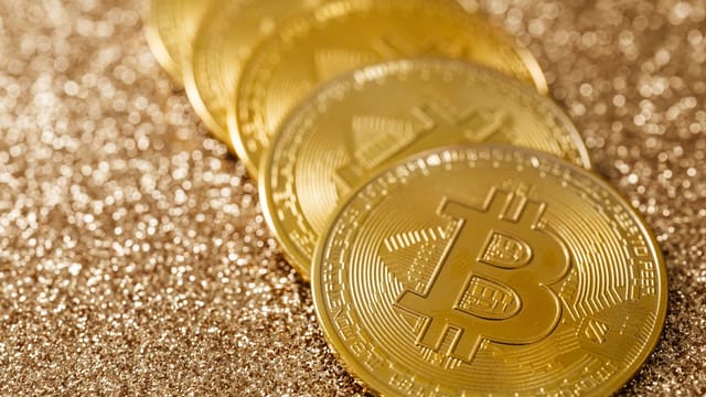 Close-up of golden Bitcoin coins on a shimmering glitter background, symbolizing digital currency's allure.