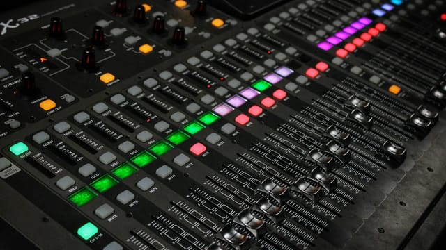 Detailed view of audio mixing console with glowing LED buttons.