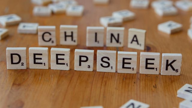 Close-up of wooden Scrabble tiles spelling 'China' and 'Deepseek' on a wooden surface.