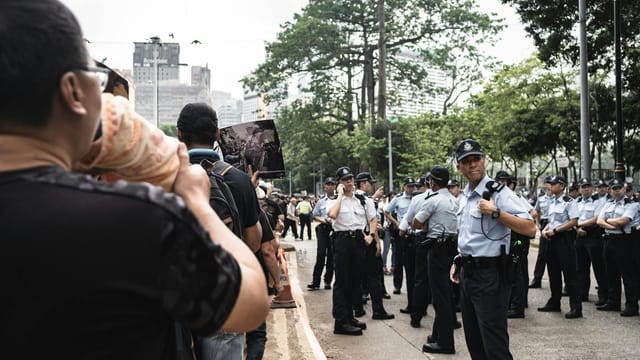 Protesters facing police officers in uniform during a public demonstration in Hong Kong city.