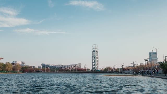 View of Beijing Olympic Park's Bird's Nest Stadium and Water Cube by a lake.