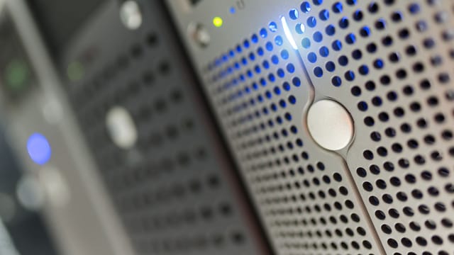 Illustrative image: Focused detail of a modern server rack with blue LED indicators in a data center.