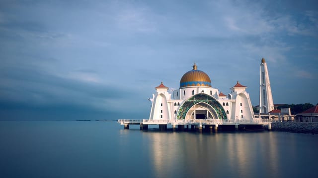 Capture of the majestic Malacca Strait Mosque in serene twilight reflecting upon calm waters.