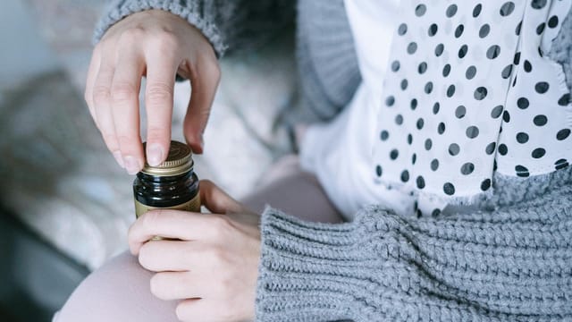 A close-up of hands opening a medicine bottle, emphasizing healthcare and recovery.