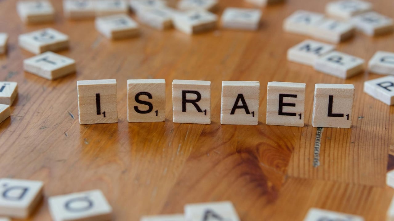 Wooden Scrabble tiles arranged to spell 'Israel' on a wooden table.
