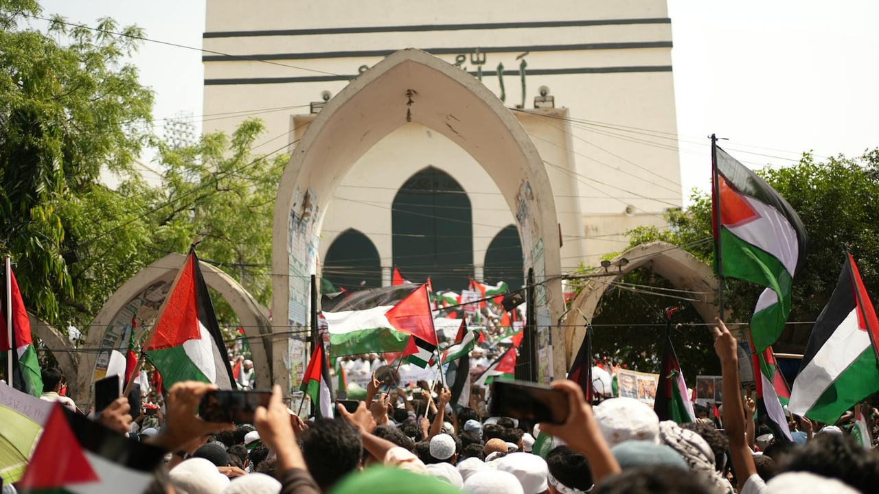A large pro-Palestinian protest in Dhaka, Bangladesh with flags and banners.