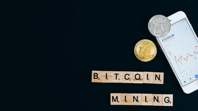 A smartphone displaying cryptocurrency trends alongside Bitcoin coins, suggesting mining.