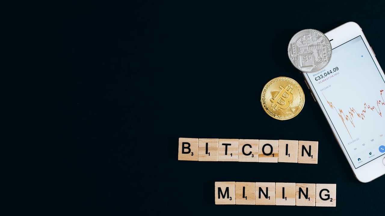 A smartphone displaying cryptocurrency trends alongside Bitcoin coins, suggesting mining.