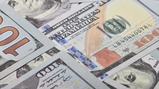 Detailed close-up of multiple US dollar banknotes showing currency details and design.